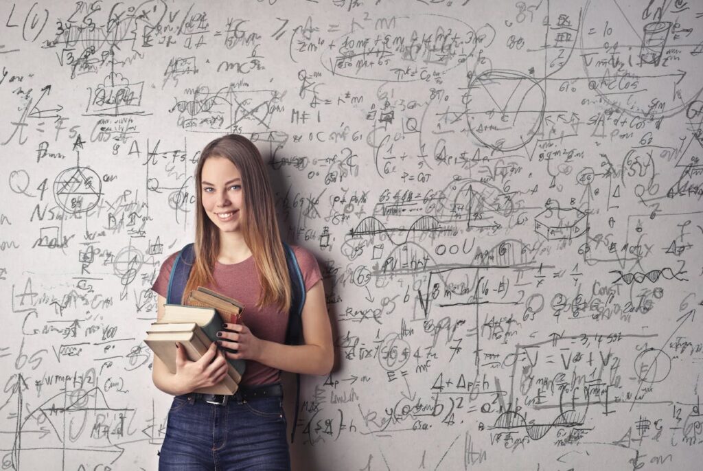 matematikle ilgili yazıların olduğu tahtanın önünde elinde kitaplar olan bir kadın